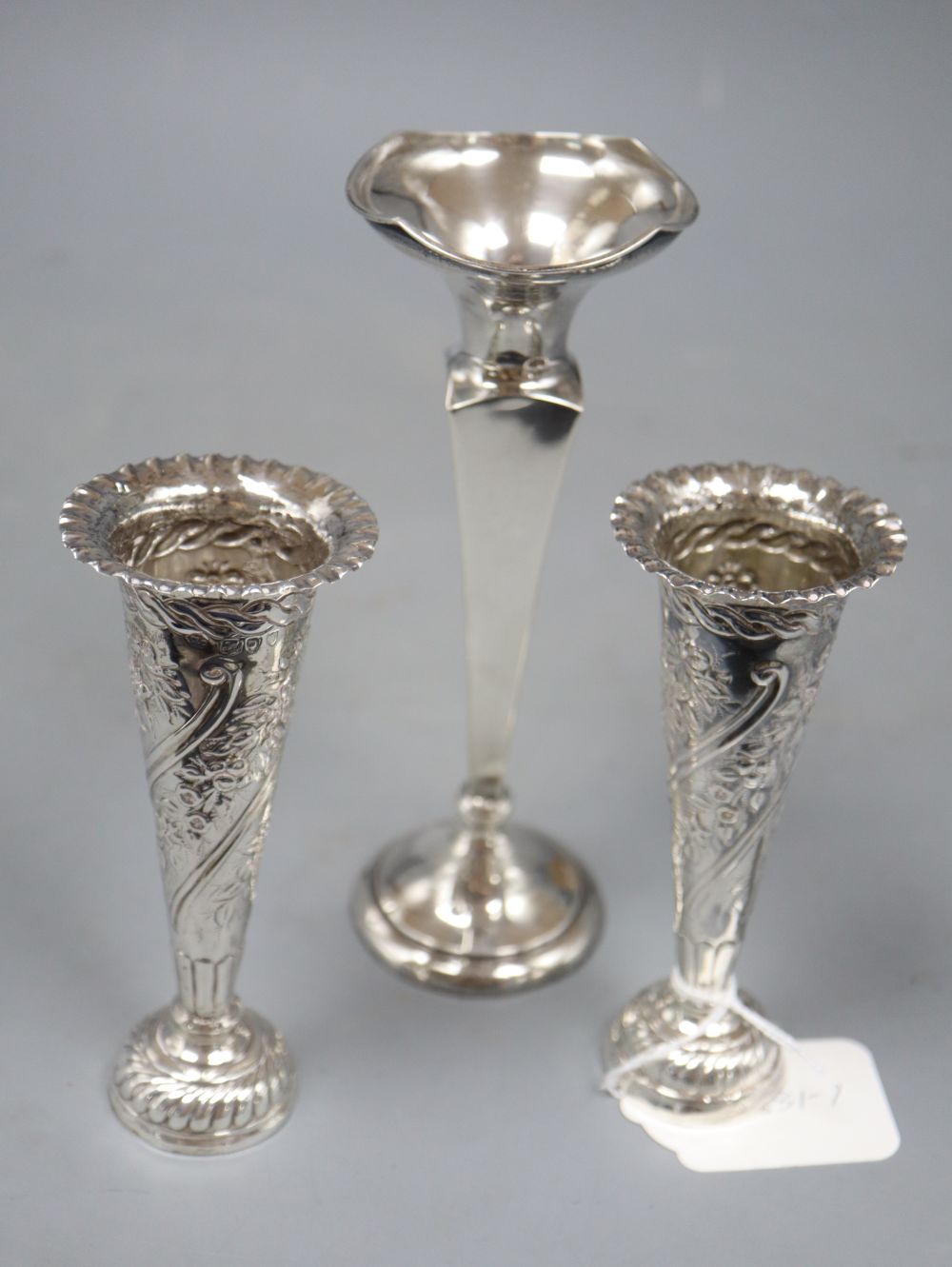A pair of late Victorian embossed silver spill vases, 13.2cm and a larger silver vase, all weighted.